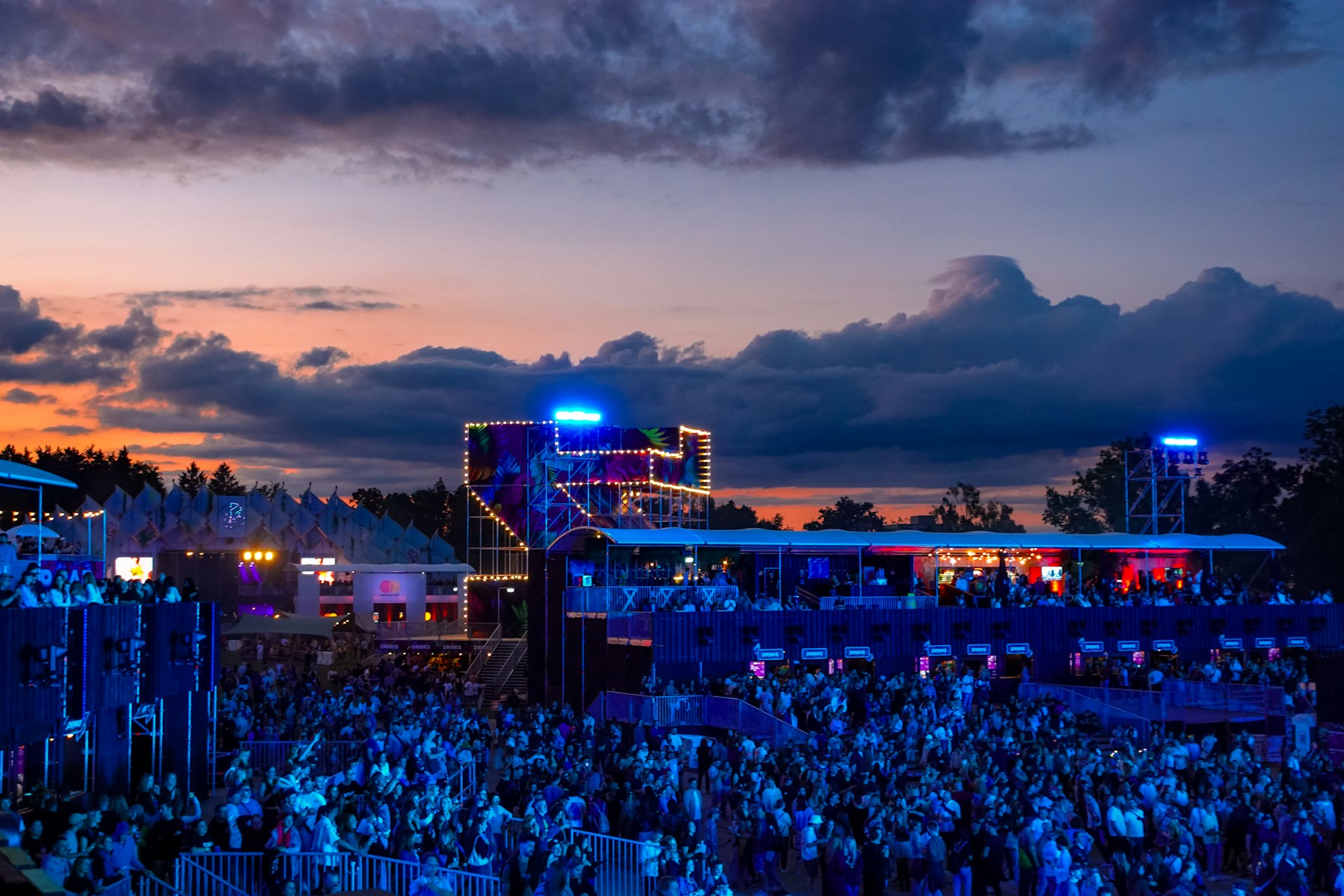A real outdoor festival crowd at dusk with temporary venue structures